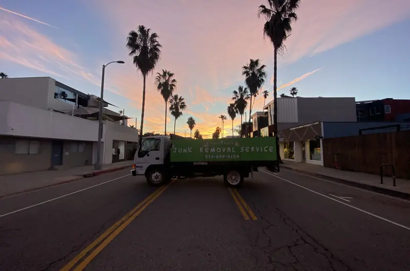 The junk removal truck on a palm-lined Venice street at sunset